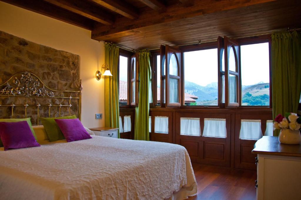 a bedroom with a bed with purple pillows and windows at Casa Rural Madre Pepa in Carreña de Cabrales