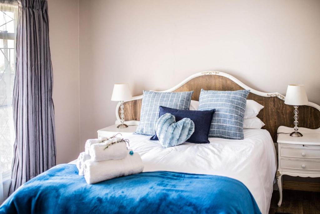 a bedroom with a bed with blue and white pillows at Opstal Gastehuis in Potchefstroom