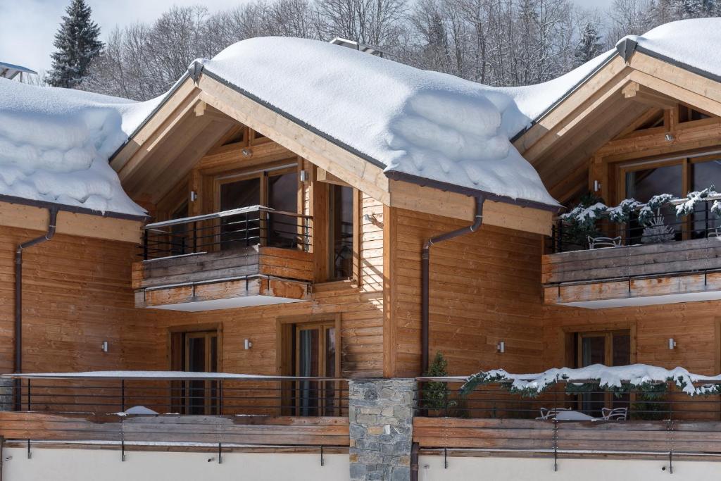 レ・ジェにあるChalet Makaluの屋根に雪が積もった木造家屋