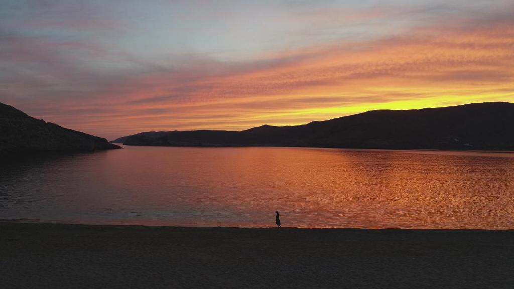 a person standing on the shore of a lake at sunset at Ammoa Beach Residences in Vayiá