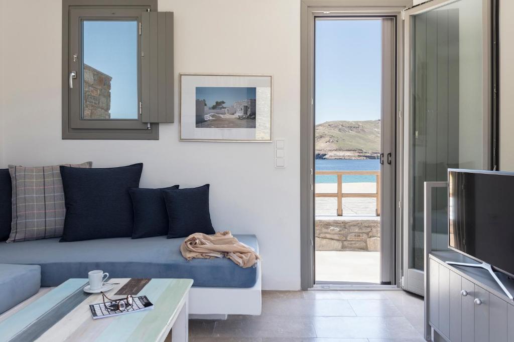 a living room with a blue couch and a tv at Ammoa Beach Residences in Vayiá