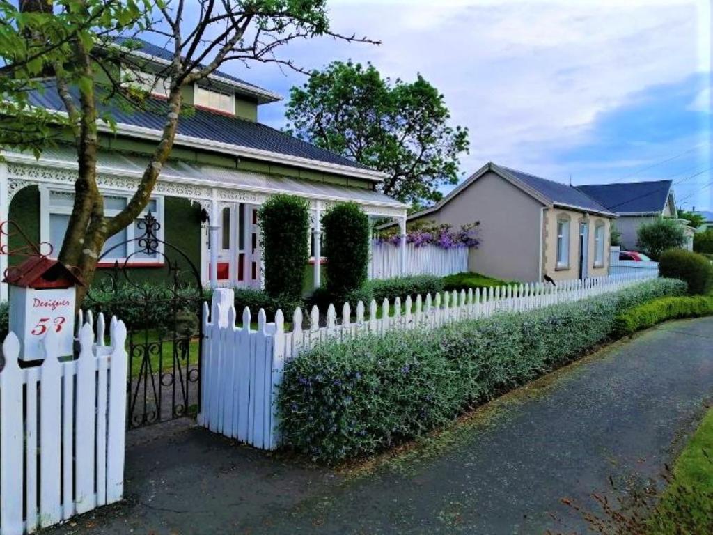 una staccionata bianca di fronte a una casa di Designer Cottage a Christchurch
