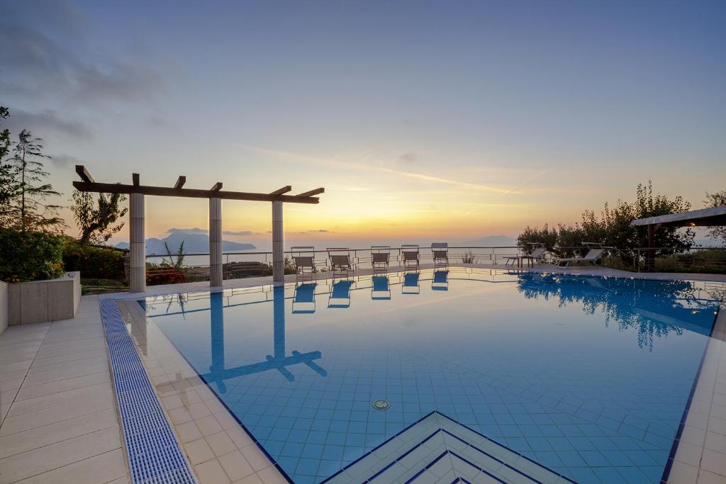 ein großer Pool mit Sonnenuntergang im Hintergrund in der Unterkunft AMORE RENTALS - Villa Elia in Massa Lubrense