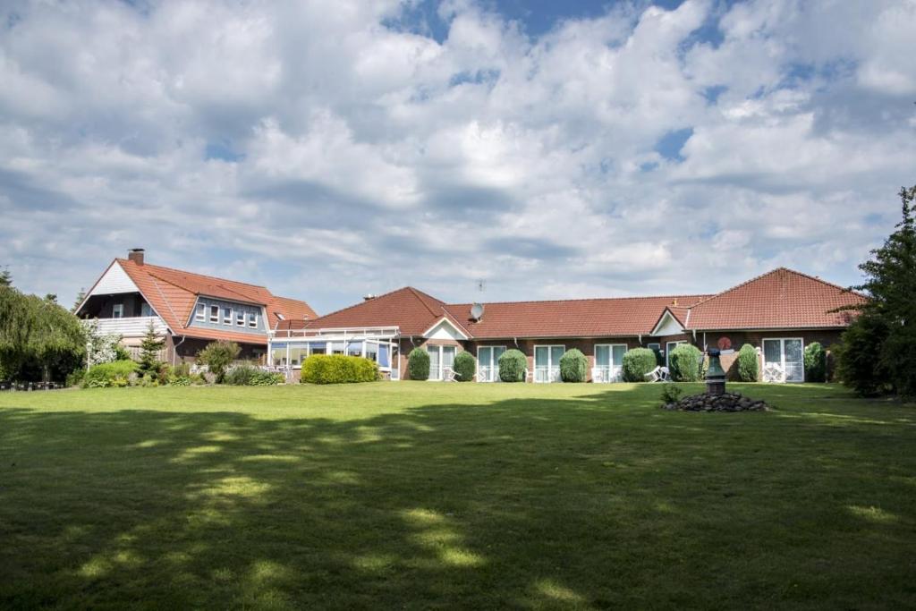 ein großes Haus mit grünem Rasen davor in der Unterkunft Hotel Am Deich in Apen