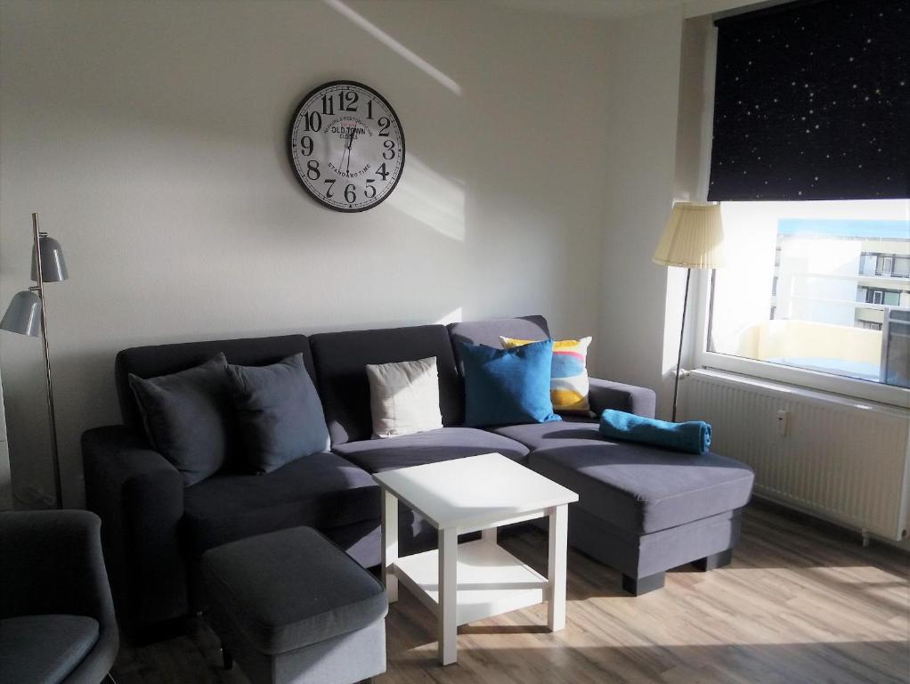 sala de estar con sofá y reloj en la pared en Vier Jahreszeiten Haus 2 Whg 46, en Großenbrode