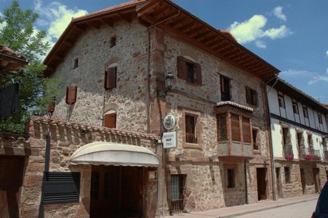 un vecchio edificio in pietra con un grande edificio di Hostal Casa Masip a Ezcaray