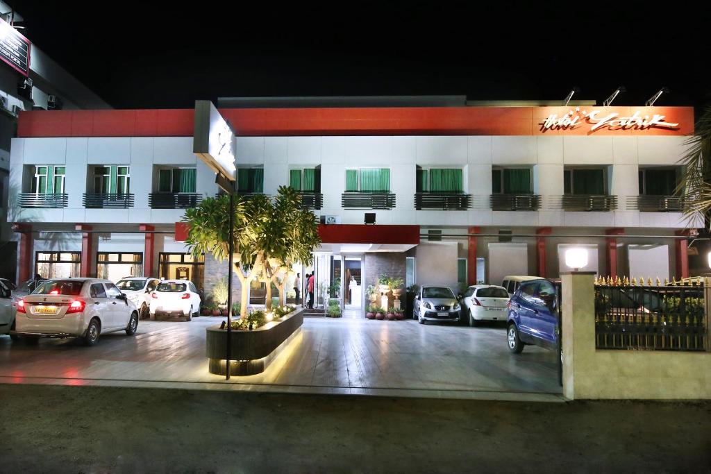 a hotel with cars parked in a parking lot at Hotel Yatrik in Allahābād