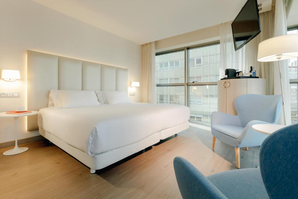 - une chambre avec un grand lit blanc et une chaise dans l'établissement Hesperia A Coruña Centro, à La Corogne