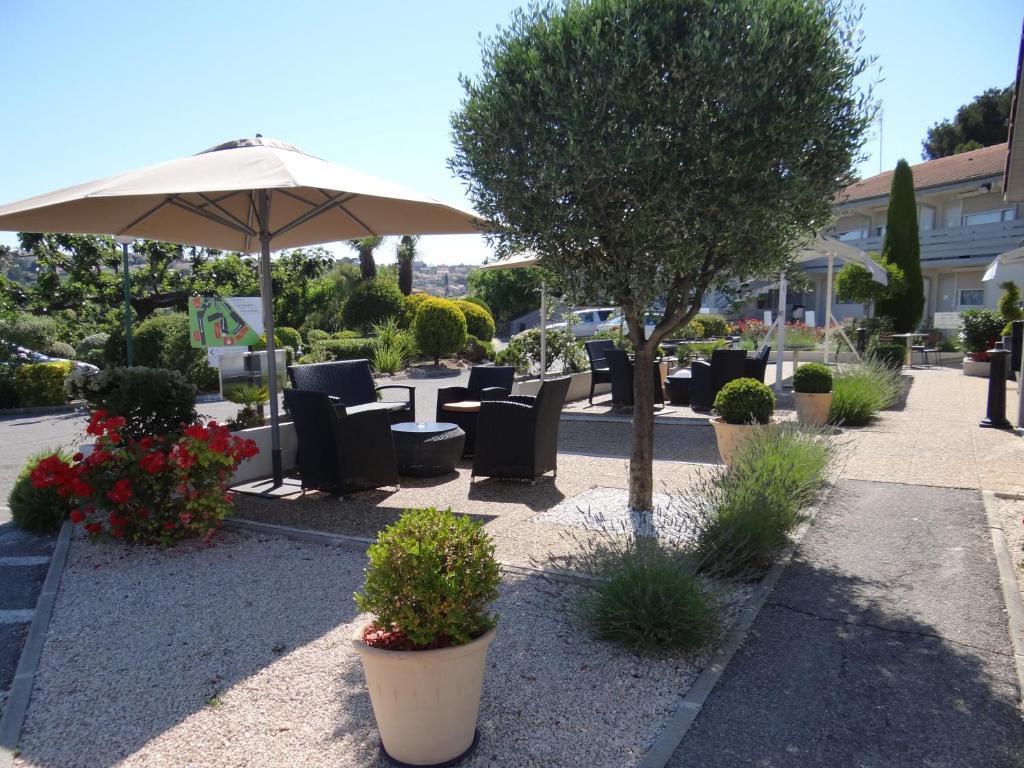 un patio con mesas, sillas y una sombrilla en Campanile Marseille Saint Antoine, en Marsella