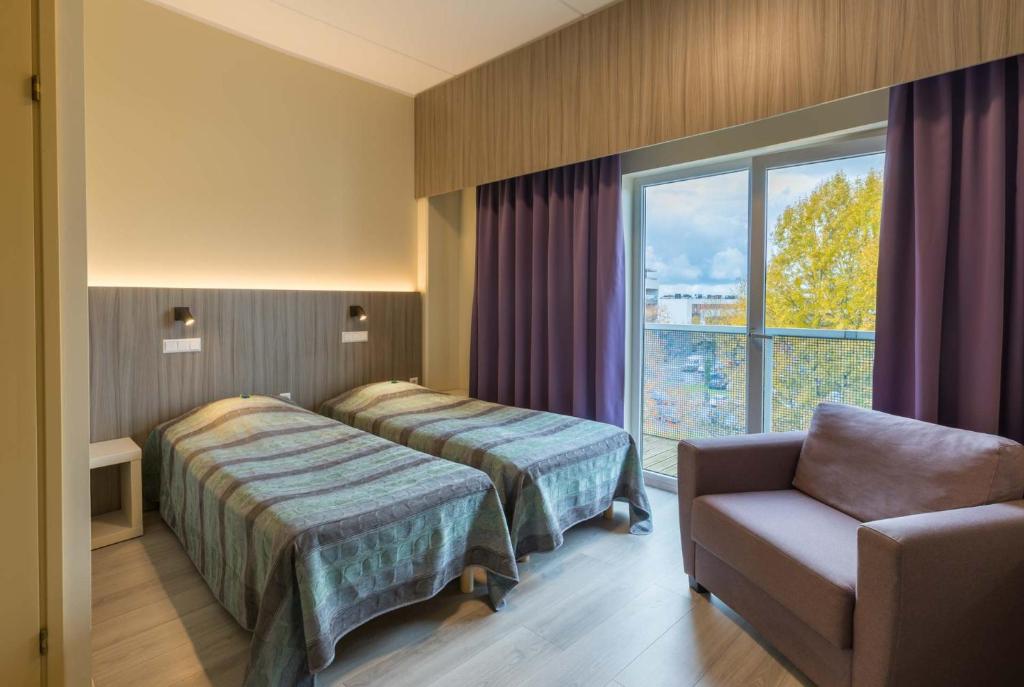 una camera d'albergo con due letti, una sedia e una finestra di Viiking Spa Hotel a Pärnu