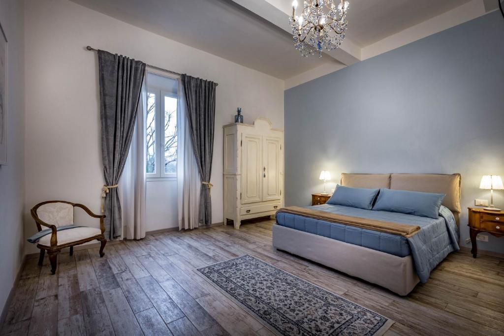 una camera con letto, sedia e lampadario a braccio di Arno Apartments a Firenze