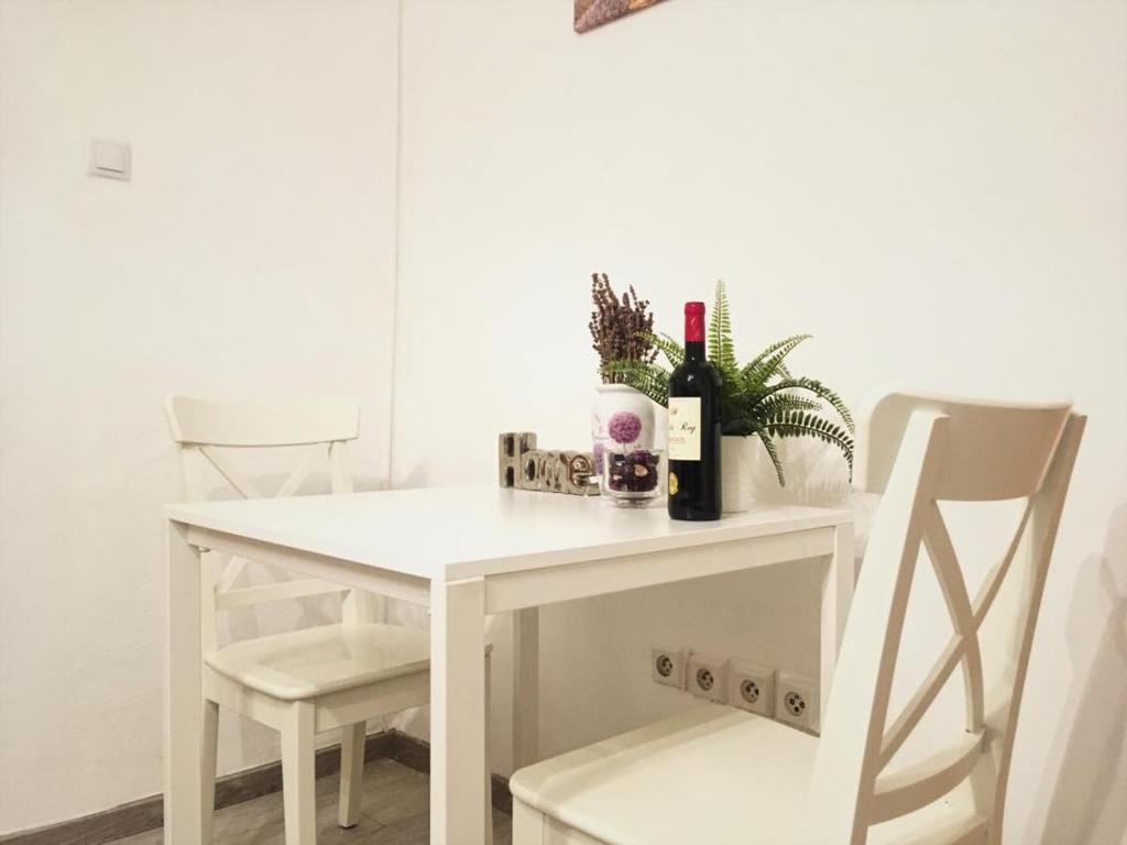 Biały stół z 2 krzesłami i butelkami wina w obiekcie Apartment Happy 11 w Pradze
