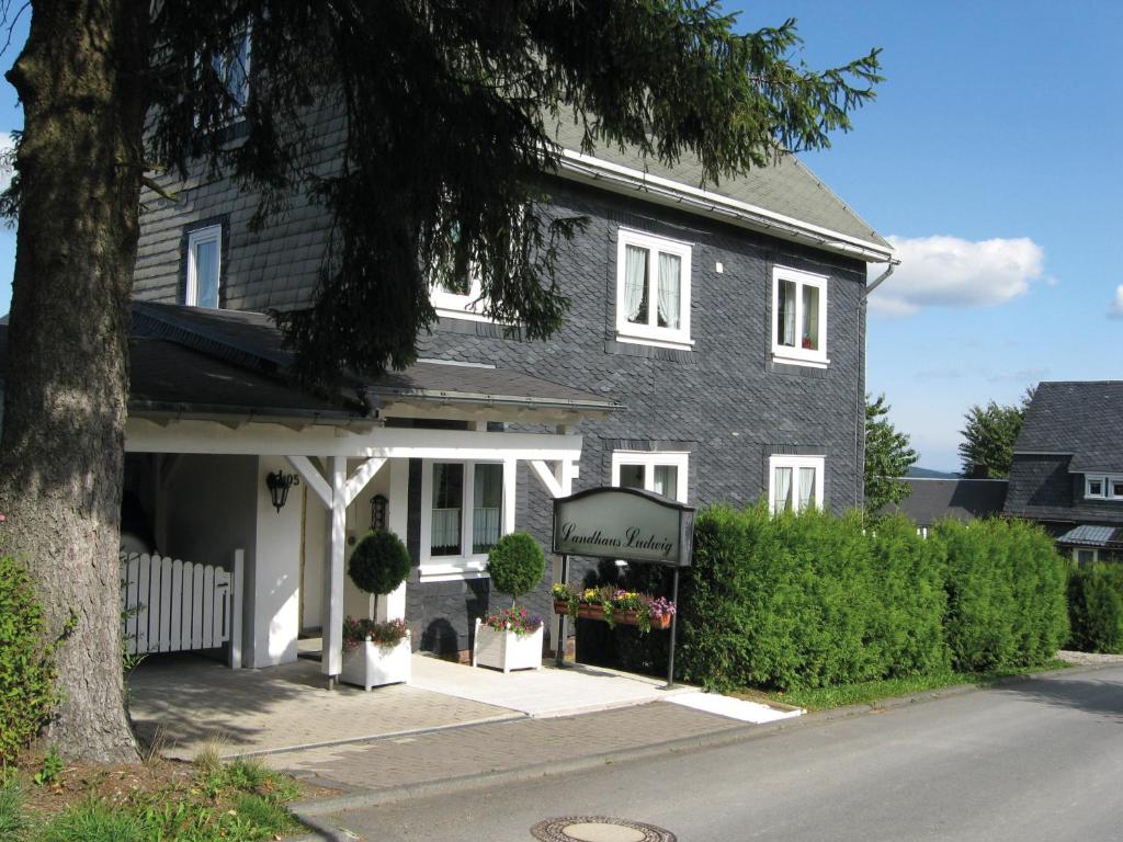 een grijs huis met een bloemenwinkel ervoor bij Ferienwohnung Waldblick im Haus Ludwig in Masserberg