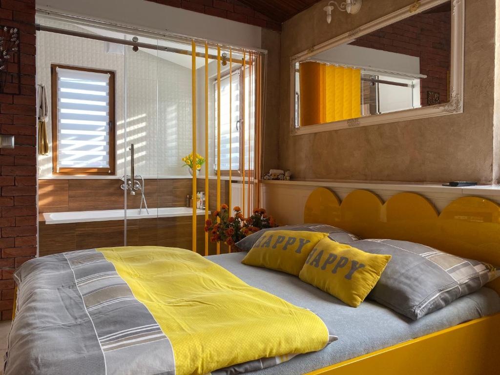a bedroom with a bed with a yellow blanket and a mirror at Klinkierowy Apartament z wanną dla Dwojga in Gniezno