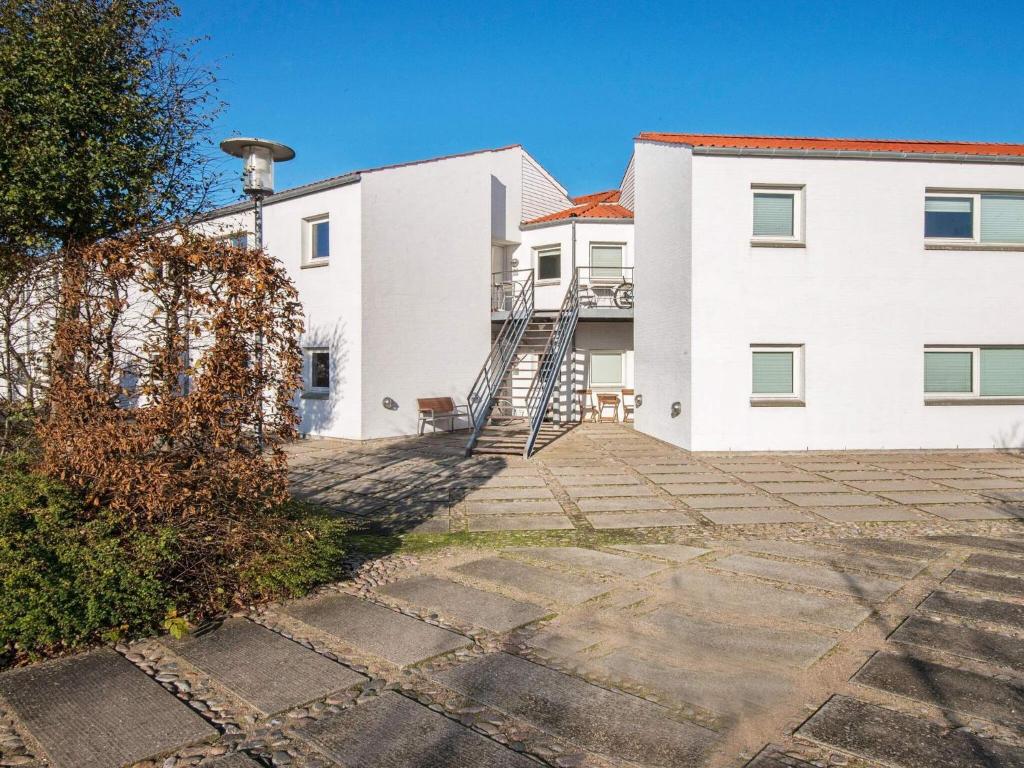 a white building with a staircase in front of it at 4 person holiday home in Ebeltoft in Ebeltoft