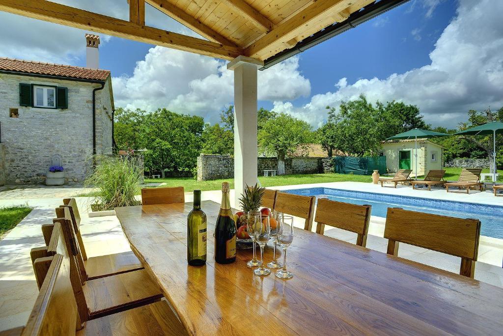 una mesa de madera con botellas de vino y copas en un patio en Villa Lucy, en Rojnići