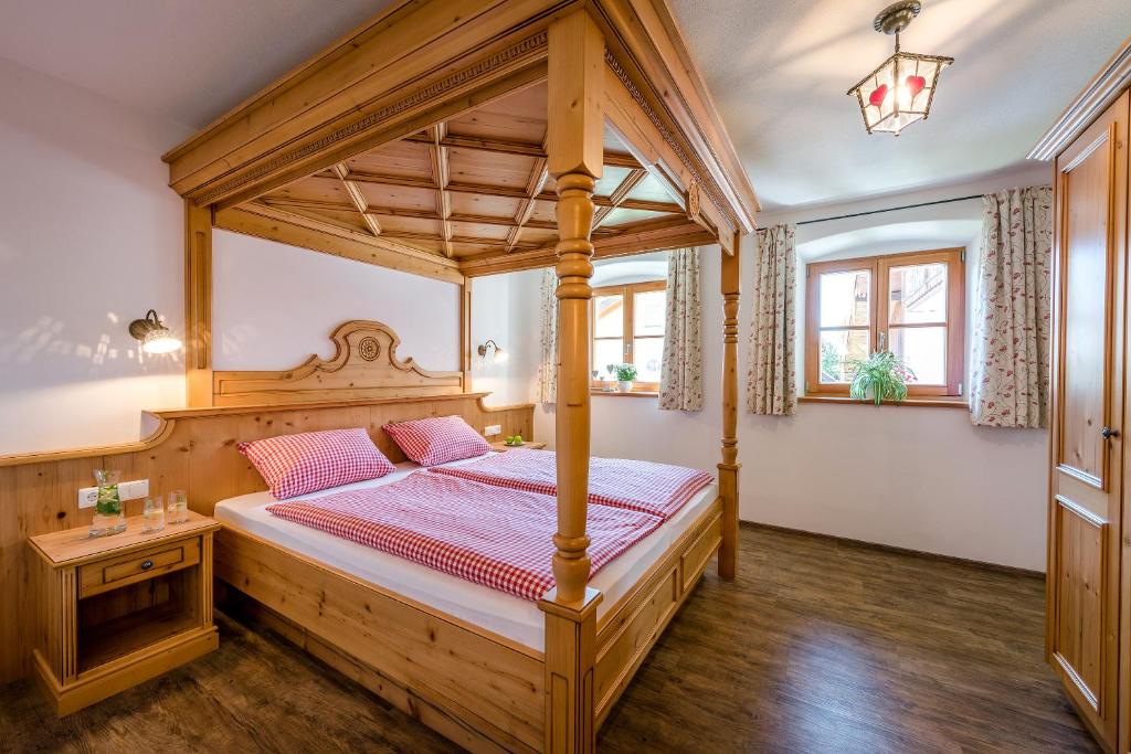 ein Schlafzimmer mit einem hölzernen Himmelbett und Holzboden in der Unterkunft Beim Paulfischer - Eckbankerl in Chieming