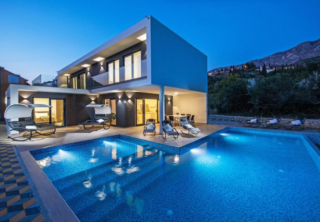 une maison avec une piscine en face d'une maison dans l'établissement Villa Holiness a luxury villa in Dubrovnik, tennis court, à Mlini