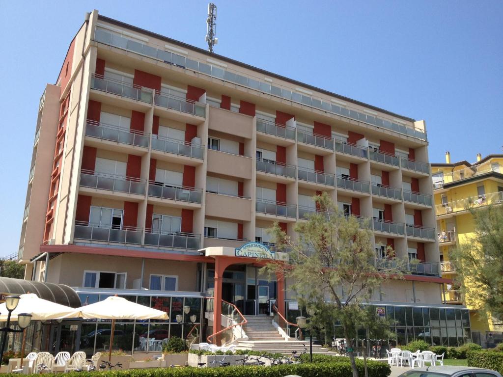 un grande edificio con tavoli e ombrelloni di fronte di Residence Capinera a Sottomarina