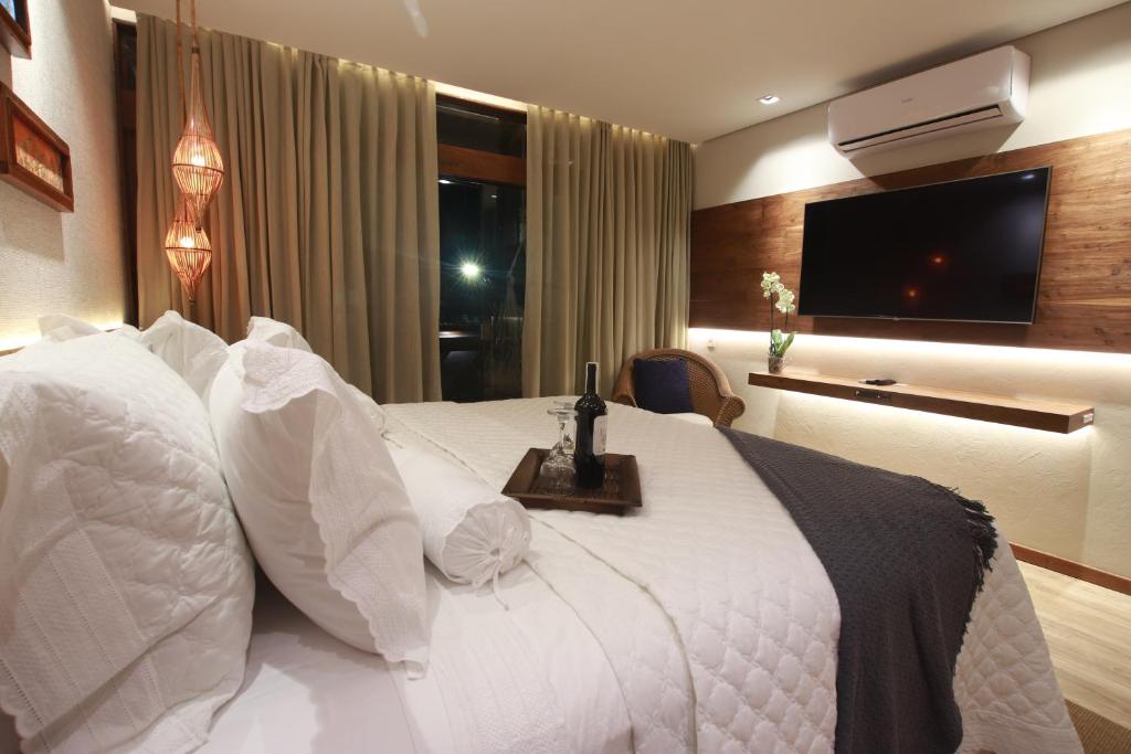 a hotel room with a white bed and a television at Pousada Meu Talento in Alto Paraíso de Goiás