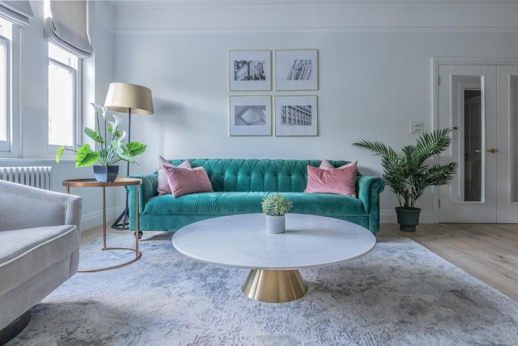 un soggiorno con divano verde e tavolo di Elysian House - Kensington Serviced Apartments a Londra