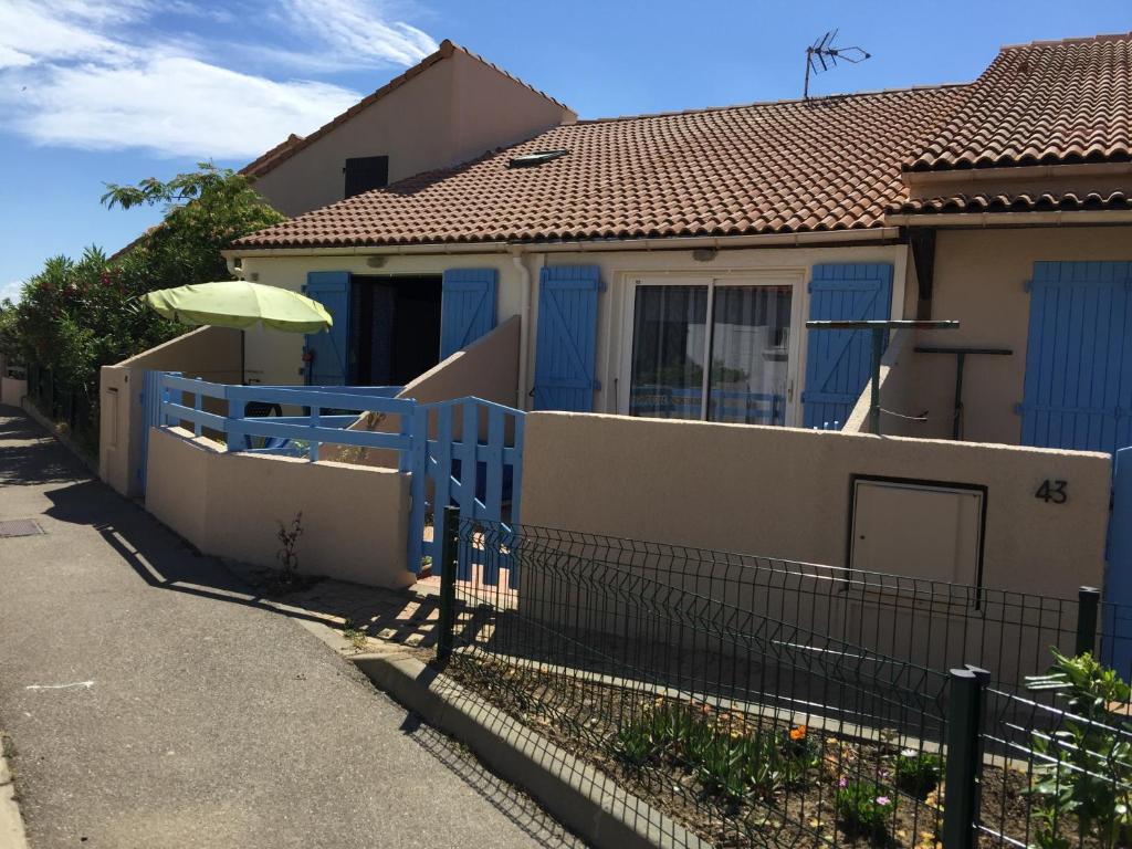 a house with a blue fence and an umbrella at Les Mas De La Mer in Port-la-Nouvelle