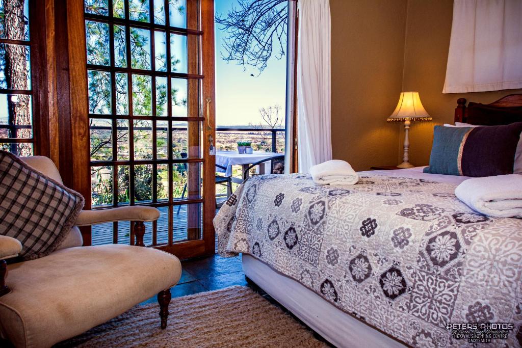 um quarto com uma cama, uma cadeira e uma janela em Buller's Rest Guest Lodge em Ladysmith