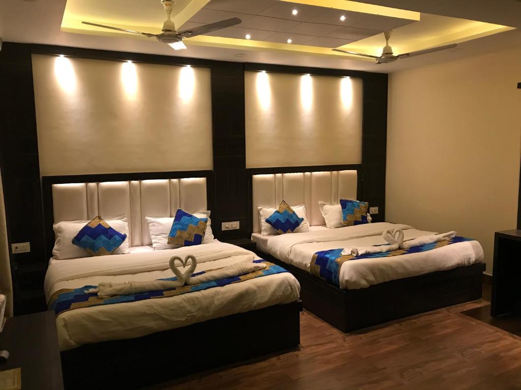a bedroom with two beds with white sheets and blue pillows at Hotel Kabir Residency in Amritsar