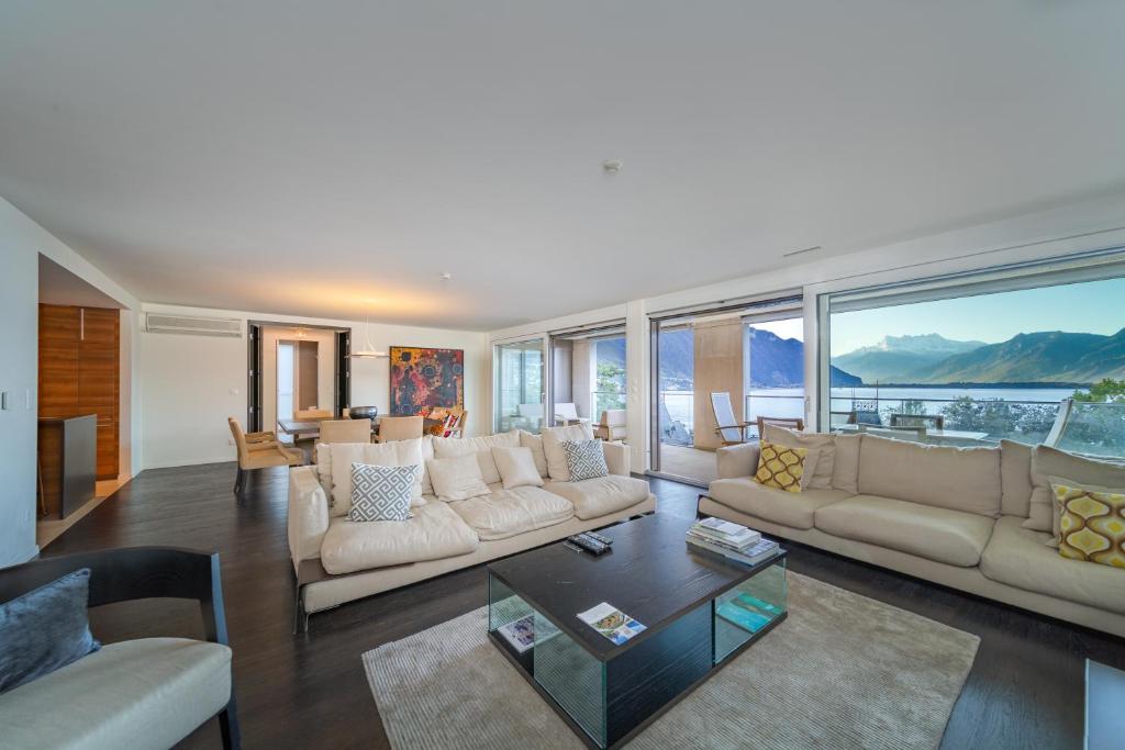 a living room with white furniture and large windows at Luxury Apartment Lake View & Center of Montreux by GuestLee in Montreux