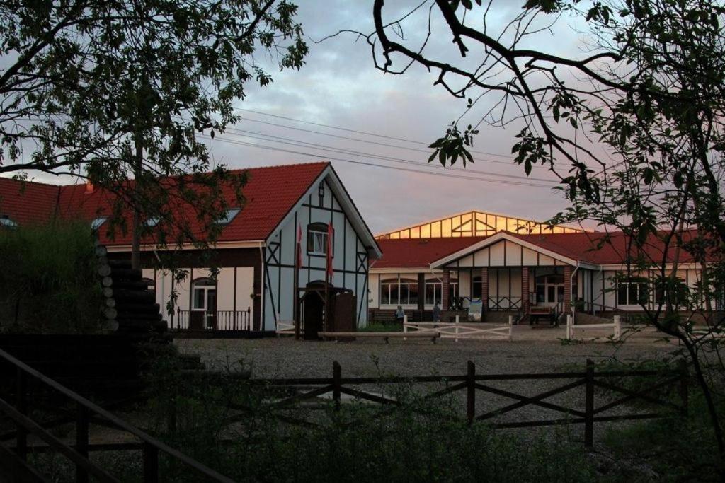 Biały dom z czerwonym dachem i płotem w obiekcie Detskaya Konnaya Akademiya Ruteniya w mieście Wsiewołożsk