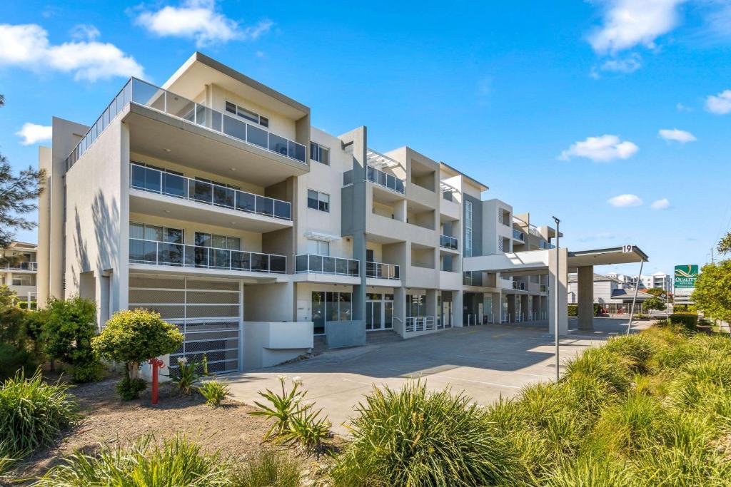 an apartment building with a pathway in front of it at Quality Suites Pioneer Sands in Wollongong