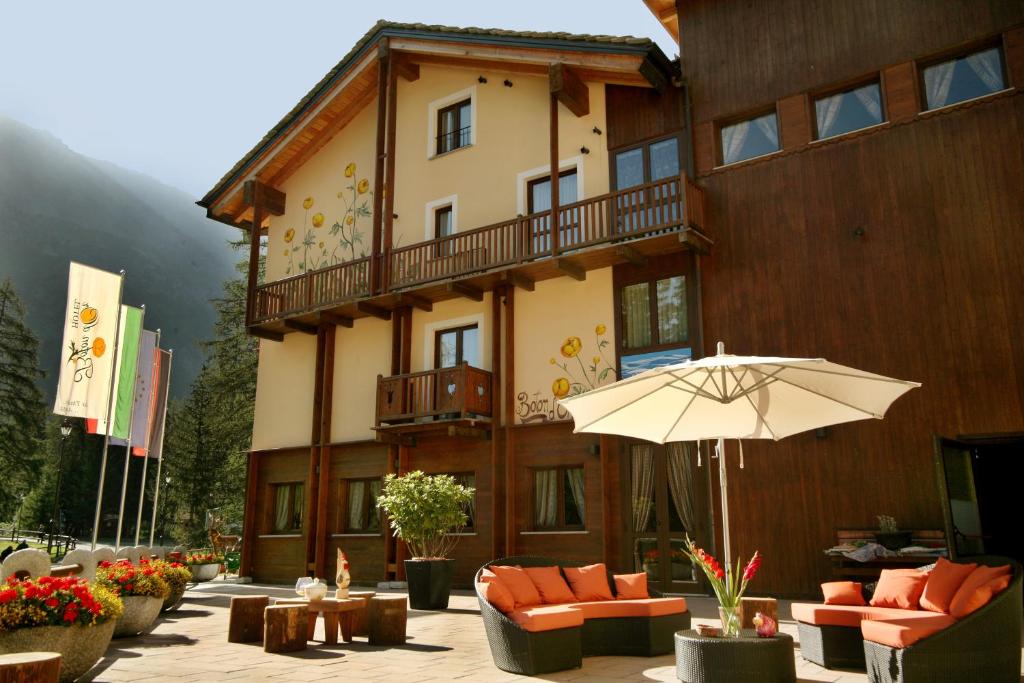 un bâtiment avec un parasol devant lui dans l'établissement Hotel Boton D'Or & Wellness, à La Thuile