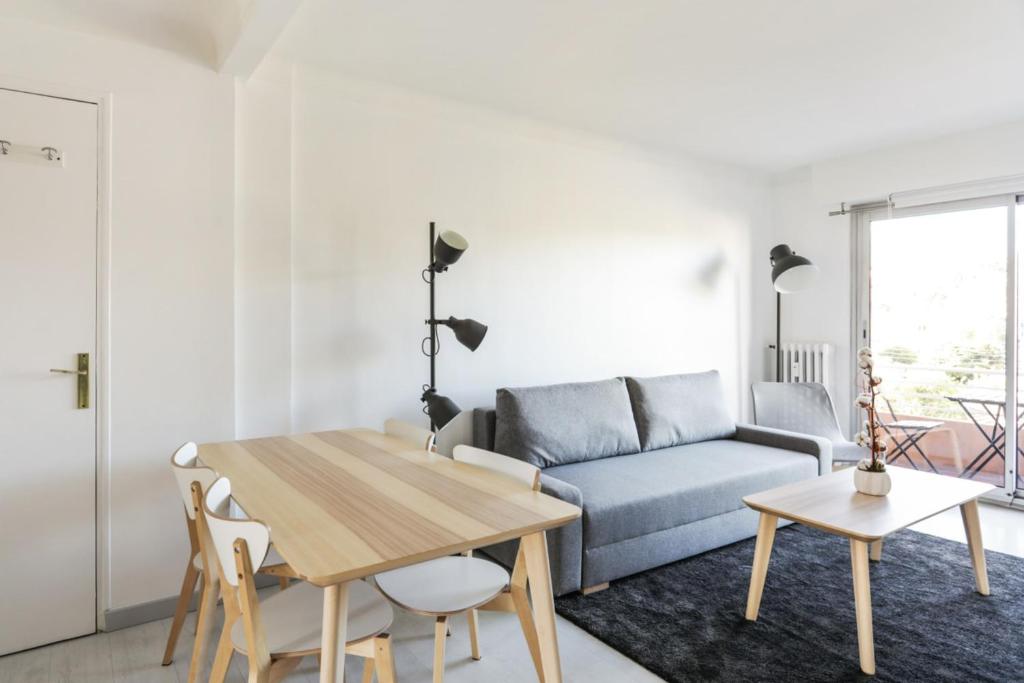 una sala de estar con una mesa y un sofá en Appartement Soleil d'Antibes - Welkeys, en Antibes