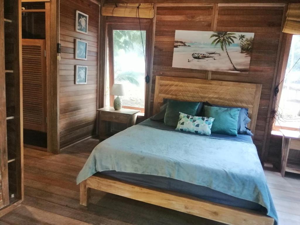 Sonny Island Resort في Punta Bajo Rico: غرفة نوم بسرير في غرفة بجدران خشبية