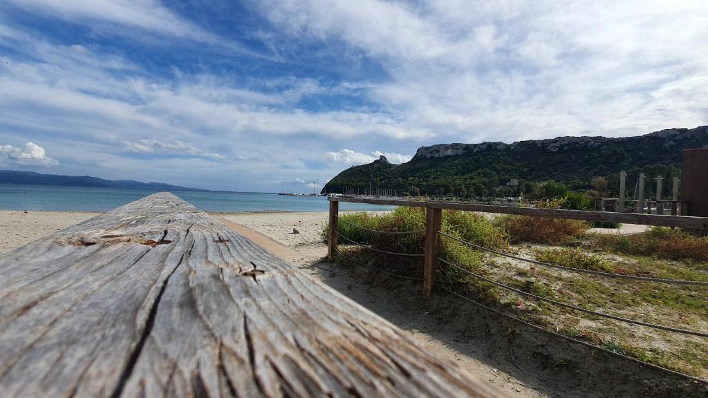 un banco de madera sentado en una playa con el océano en EM Holiday Apartment, en Quartu SantʼElena