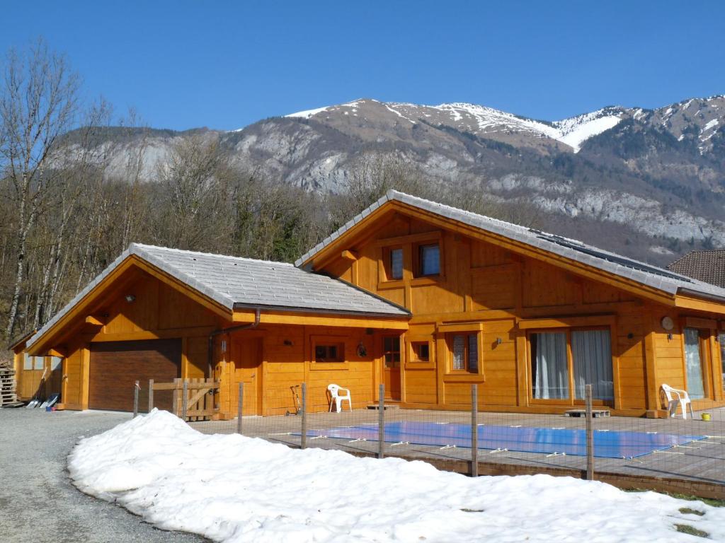 a log cabin with snowy mountains in the background at Chalet aux 3 biches in Mieussy