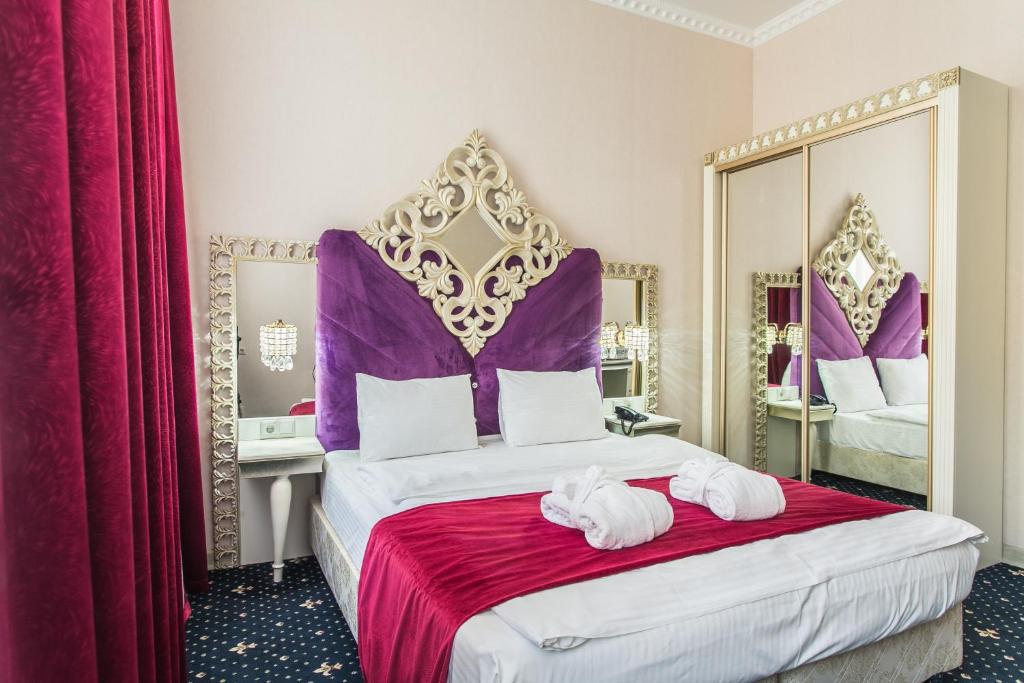 a bedroom with a king sized bed with purple accents at Отель НЕАПОЛЬ in Moscow