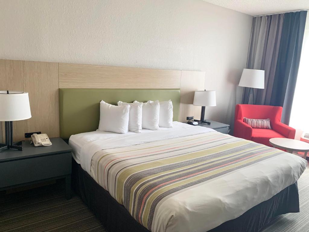 a hotel room with a large bed and a red chair at Sonesta Essential IAH Airport JFK Boulevard - Newly Renovated in Houston