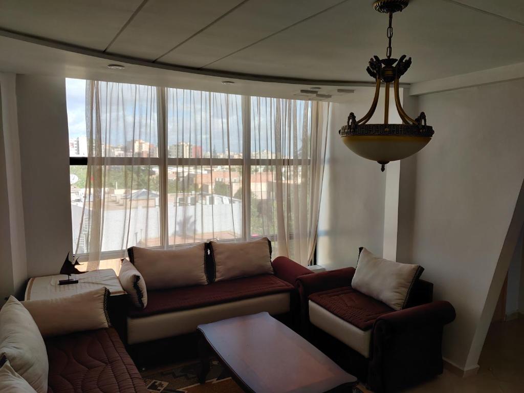 a living room with couches and a large window at Appartement Wynwood 3 in Oujda