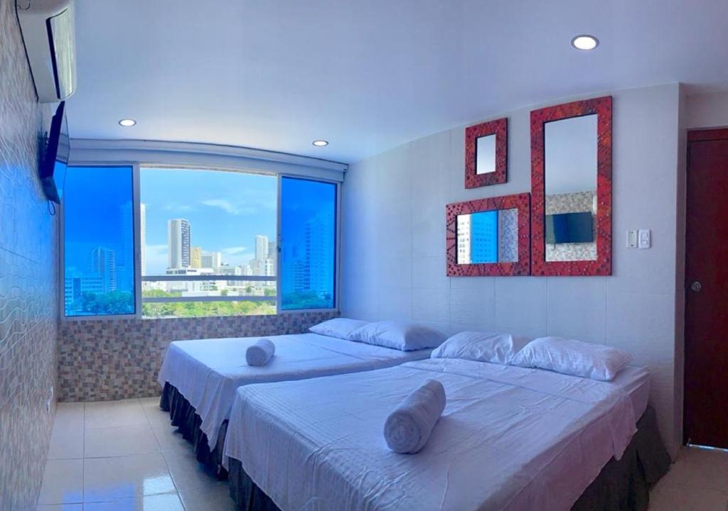 a bedroom with two beds and a large window at PyEnsa Cartagena in Cartagena de Indias