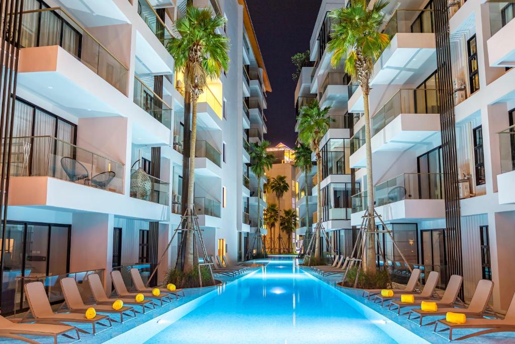 an image of an apartment building with a swimming pool and palm trees at Surin Beach Residence in Surin Beach