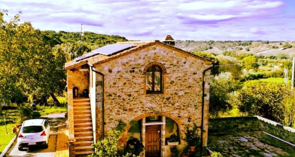 uma pequena casa de tijolos com um carro estacionado ao lado em San Paterno B&B em Rapolano Terme