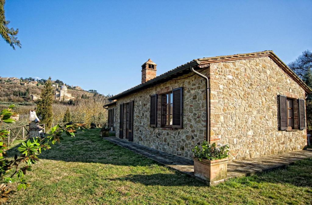 an old stone house with a chimney in a yard at Agriturismo Pescaia in Montepulciano