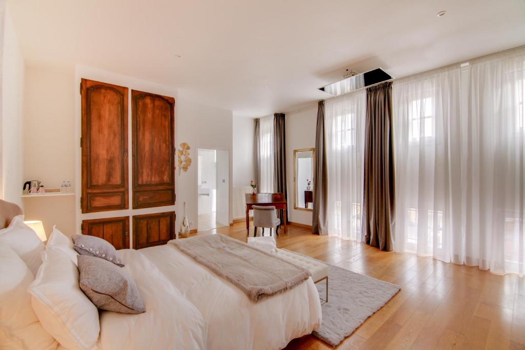 a white bedroom with a large bed and a table at Maison d'hôtes La Villa des Ducs Bar-le-Duc in Bar-le-Duc