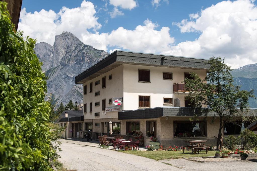 un edificio con mesas y sillas frente a una montaña en Les Sorbiers Appartements en Montricher-Albanne