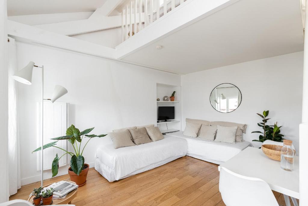 a living room with white furniture and a white couch at Appartement Vertus in Paris