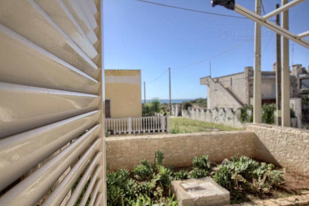 due foto di una recinzione accanto a un edificio di Casa Nitti a Lido Marini