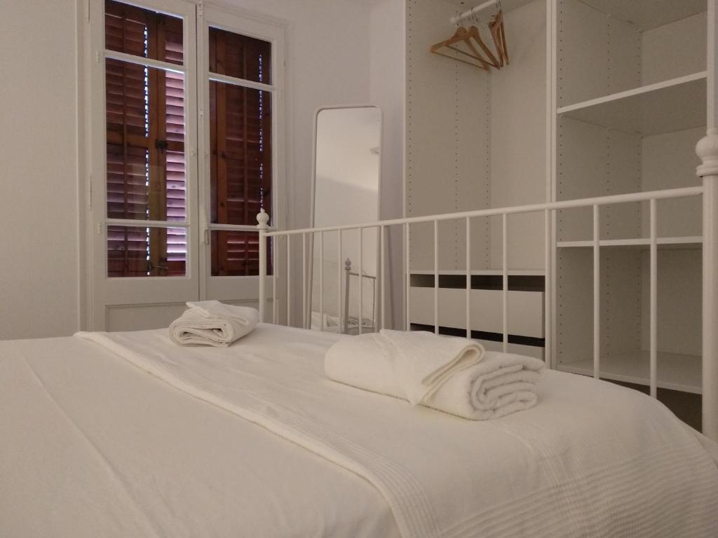 1 dormitorio blanco con 2 toallas en una cama en Apartamento 2 Cal Genís - WIFI, en Montmajor