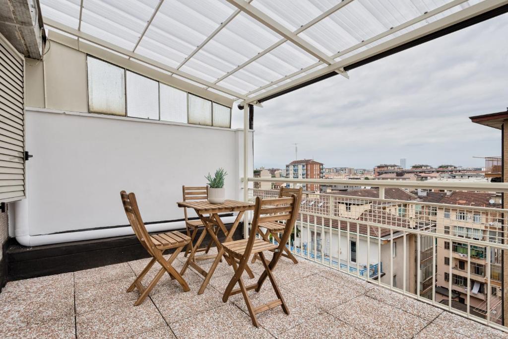 eine Terrasse mit einem Tisch und Stühlen auf dem Balkon in der Unterkunft Urban House Carducci - Attic in Turin
