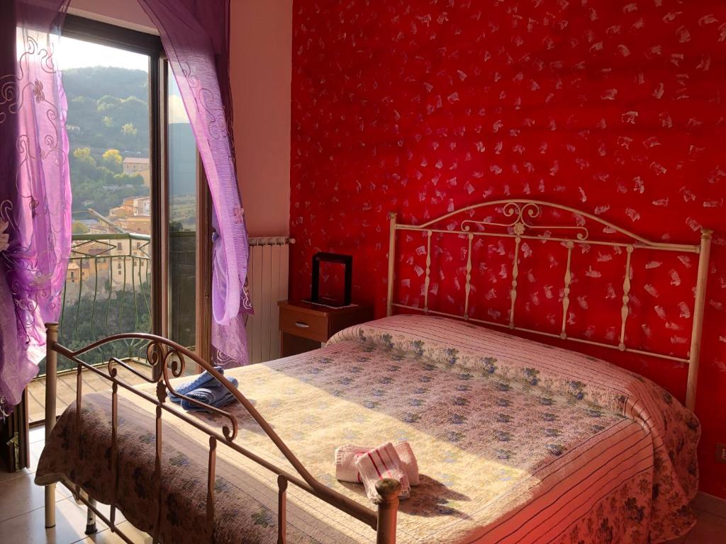 a bedroom with a bed with a red wall at Al Castello in Castelmezzano